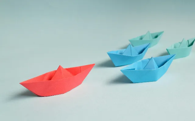 colored paper boats following each other