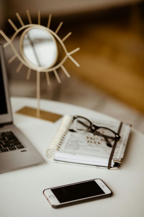 desk with journal, laptop, and phone
