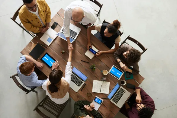 group working at table, two of which shaking hands